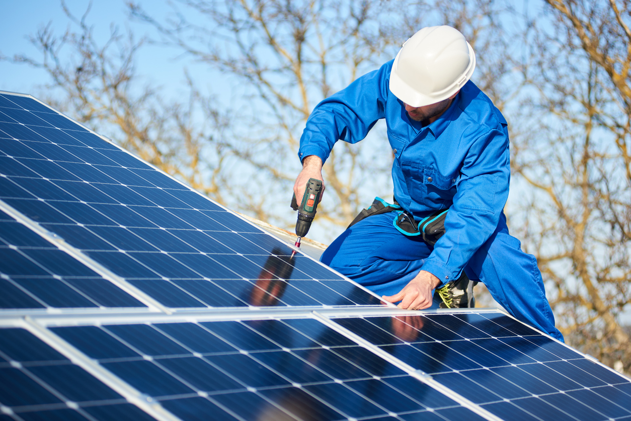 electrician-mounting-solar-panel-on-roof-of-modern-house